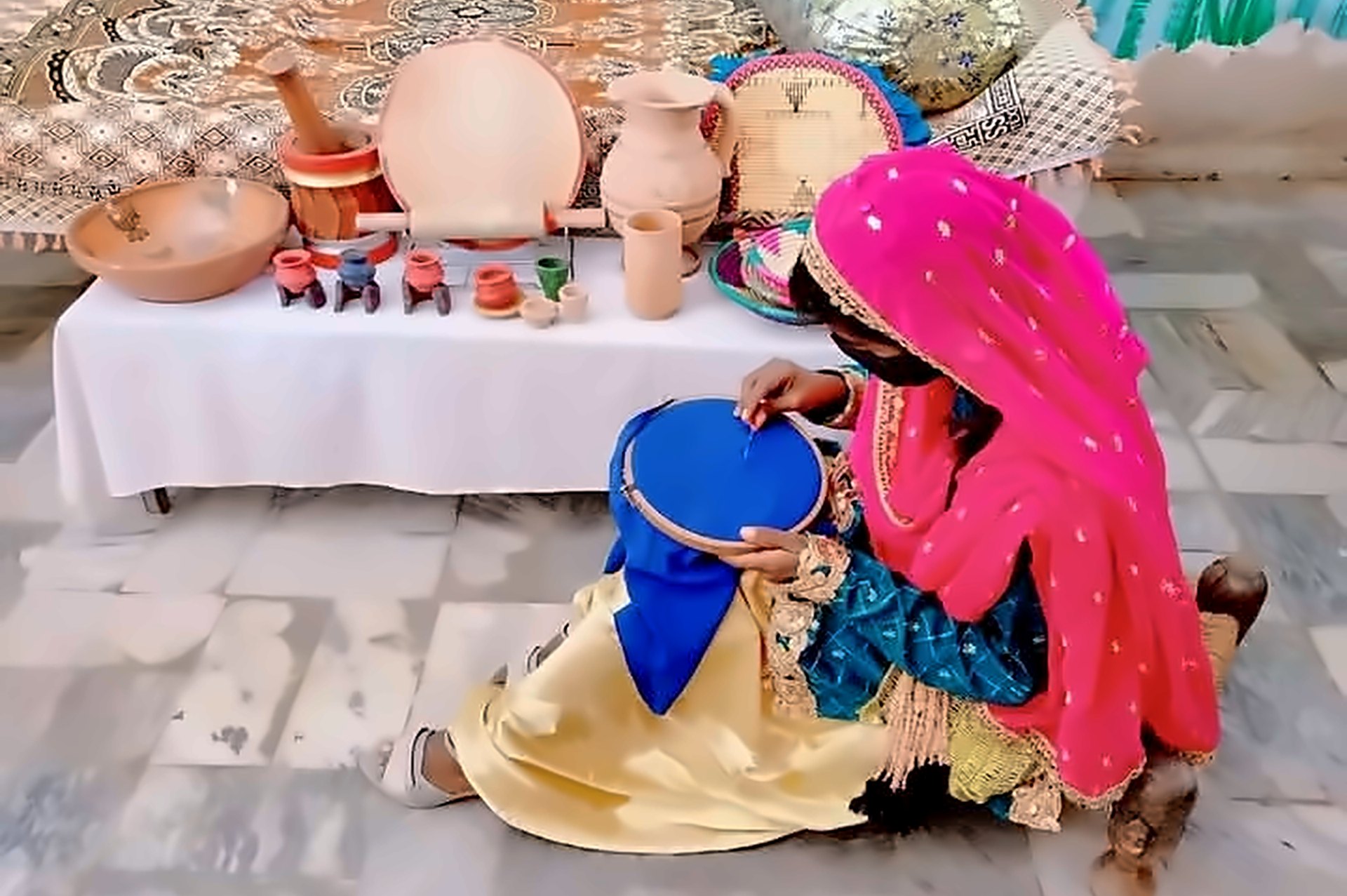 A student doing embroidery beside a display of pottery and handicrafts
